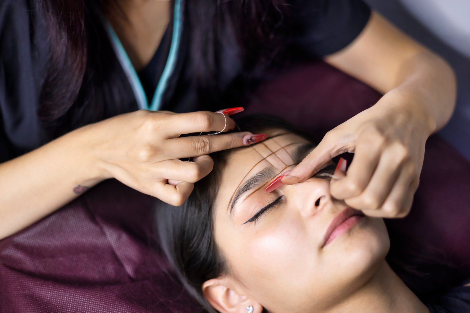 Stylist performing threaded eyebrow design